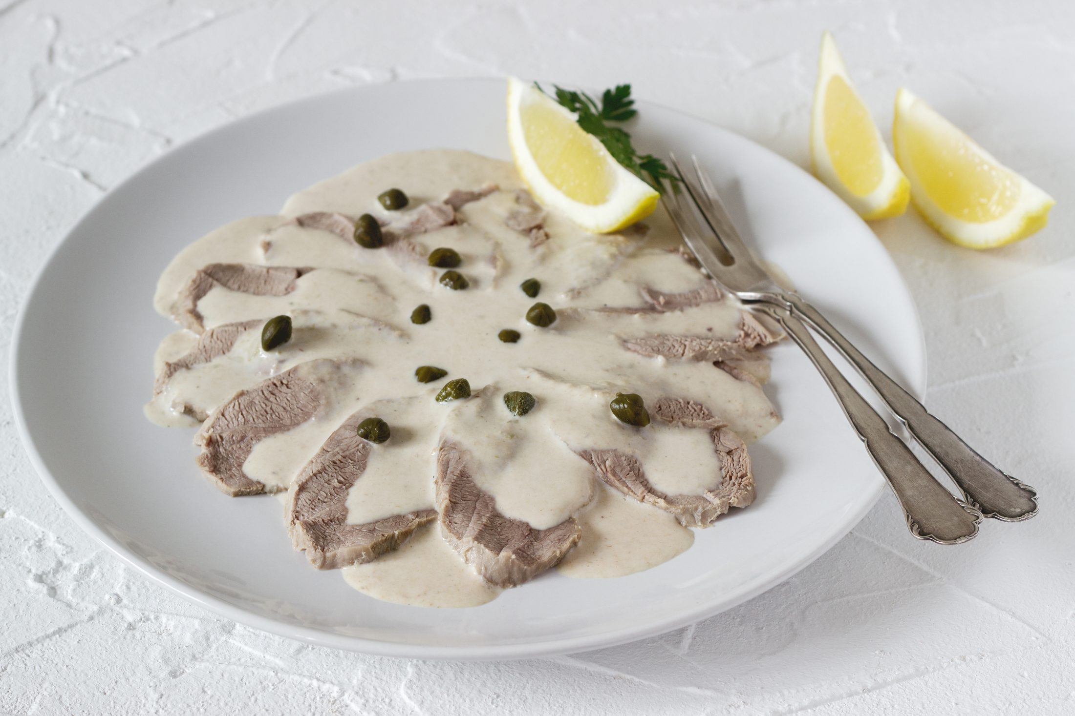 Vitello tonnato is a traditional italian dish on a white concrete background. Selective focus.